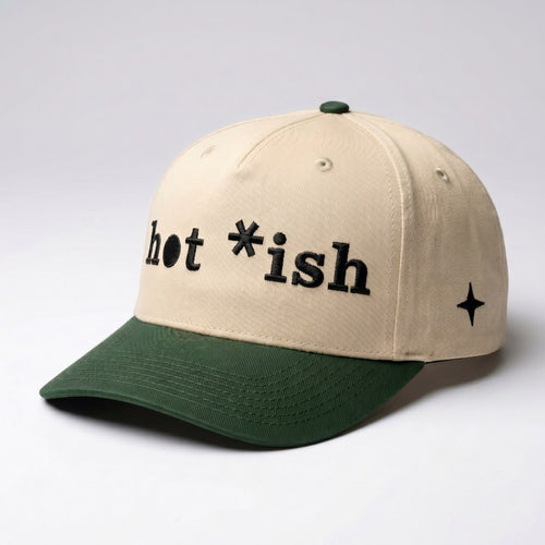 Hat with cream-colored crown and dark green colored bill that that says "hot *ish on front in stylized black embroidery, with black embroidered 4 point north star on left panel