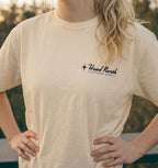 Model showing front of beige T-shirt with black and blue Head North Clothing Supply logo