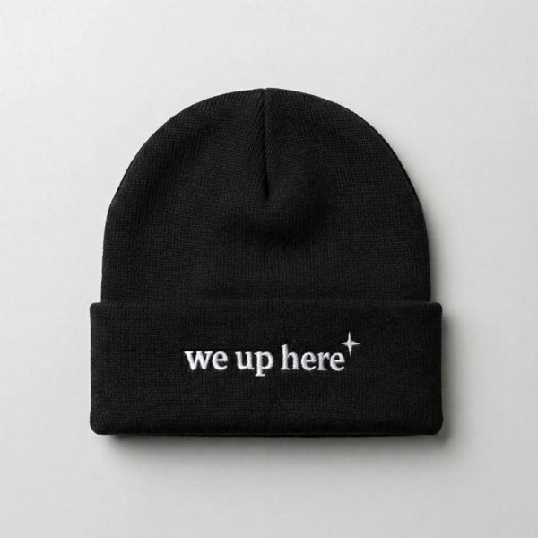 Black cuffed beanie with "we up here" embroidered in white text, and a small white north star accent